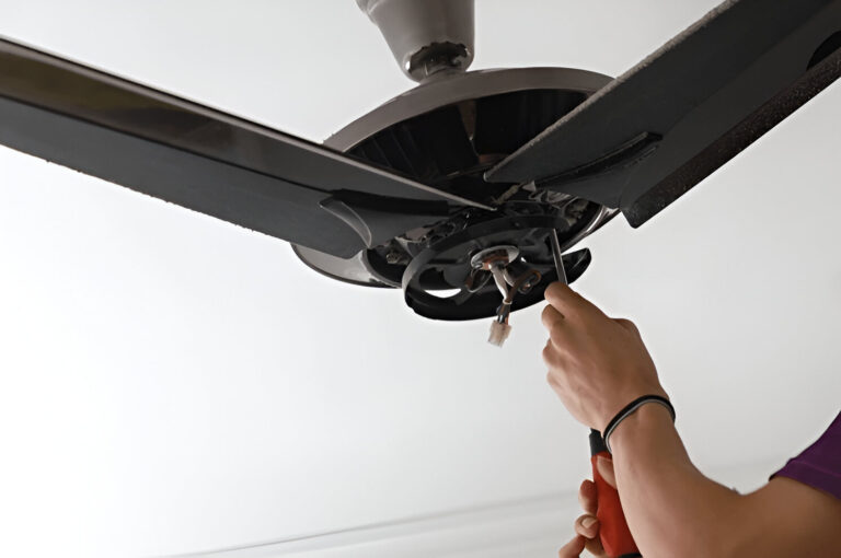 A person uses a tool to repair or complete replacement fan installations, carefully adjusting components near the motor housing.