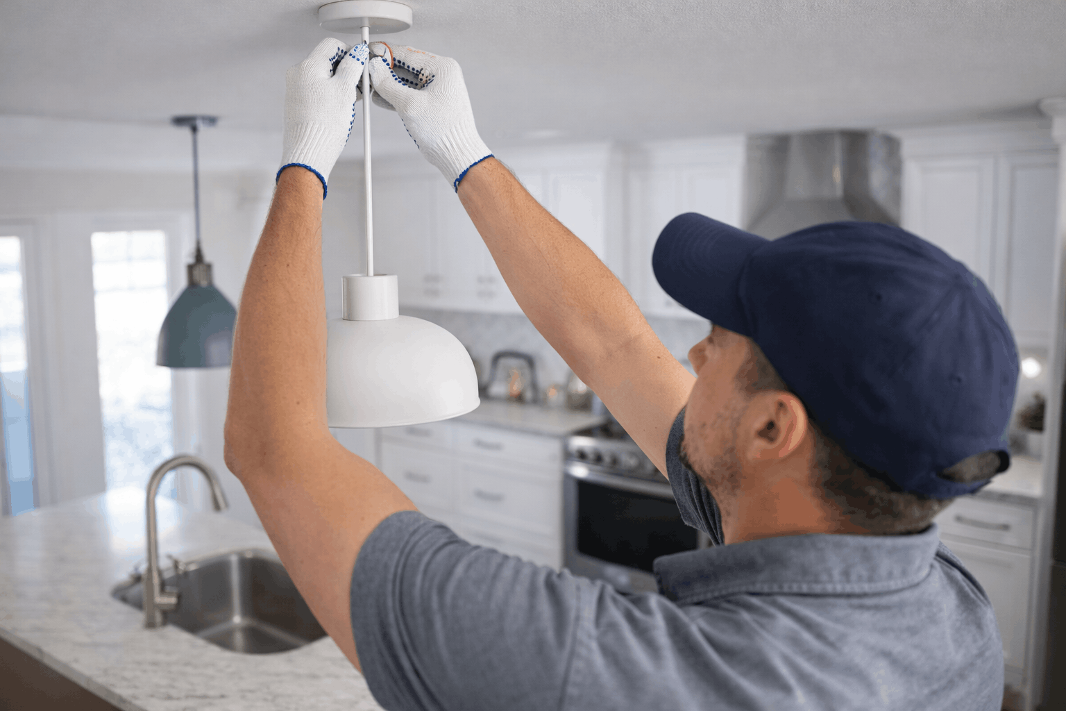 Electrician installing pendant light above kitchen island