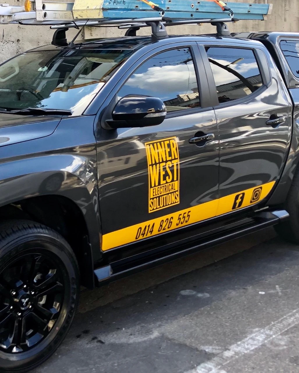 A dark grey utility pickup with ladders and Inner West Electrical Solutions sign is parked on Croydon.
