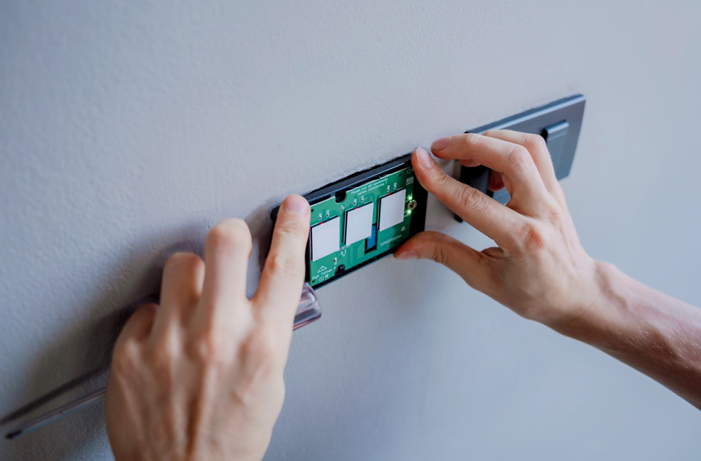 Inner West Electrical Solutions electrician installs a kinetic smart light switch panel onto a white wall.