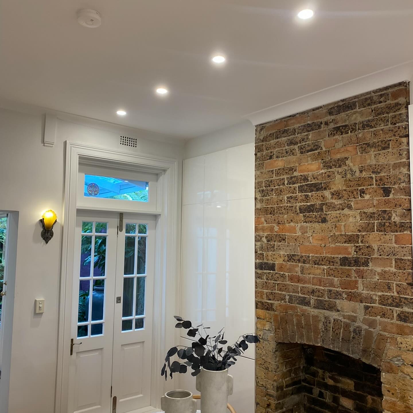 LED downlights installation in an Inner West home, featuring a bright ceiling above a brick fireplace area.